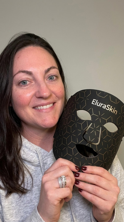 Customer Tuvan holding the black EluraSkin mask and smiling